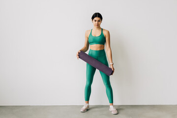 Fototapeta premium Sporty woman holding yoga mat before or after fitness class on white background