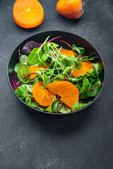 persimmon salad lettuce green leaves mix healthy meal food snack on the table copy space food background vegan or vegetarian food