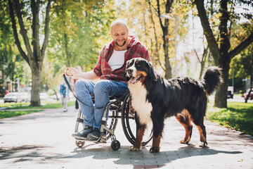 Happy young man with a physical disability who uses wheelchair with his dog.