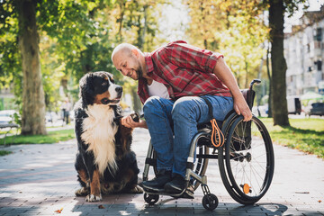 Happy young man with a physical disability who uses wheelchair with his dog.