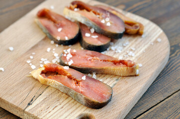 Salty fish. Pieces of salted salmon on a wooden cutting board and sea salt