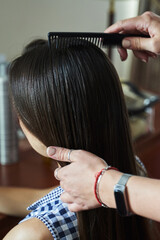 hairdresser's hands combing female hair with a thin comb