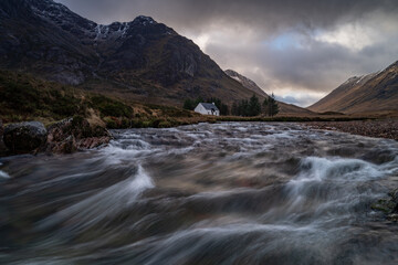 Fototapeta na wymiar Glencoe Scottish Highlands, landscape photograph of mountains and river in Scotland United Kingdom on a stormy day. Longer exposure has shown water movement in the fast flowing river