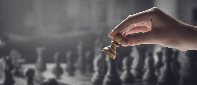 Chess player holding a piece and chess game in the background