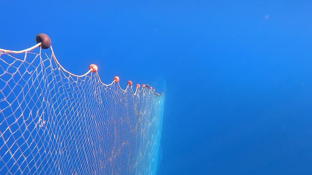 4K.Fishing net hanging from the boat under the sea.Underwater fishing of deep blue ocean.Spiral line fish nets.Tulle stretching into infinity.Trap snare ambush decoy lure ensnare entrap ambuscade net.