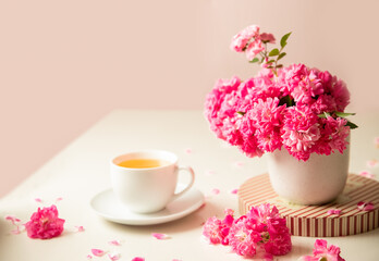 roses and tea cup served for breakfast on plain background, copy space for text, valentine's day, wedding or anniversary morning decorations