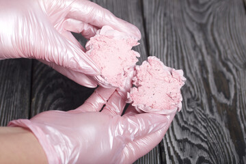 A woman holds a cut marshmallow in her hands. Against the background of pine boards. Close-up.