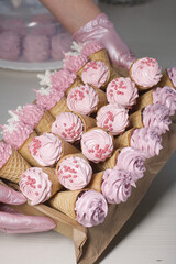 A woman holds a tray of marshmallows in waffle cones. Decorated with decorative sprinkles and mastic snowflakes. Close-up.