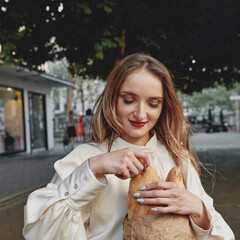 girl walks around the city French baguette in her hands