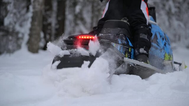 sports snowmobile rides and jumps in the snow in the forest