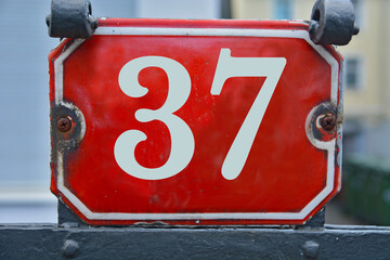 A red number plaque, showing the number thirty-seven, 37