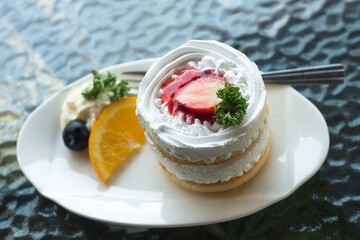 Strawberry Cake White cream on a plate decorated with oranges and blueberries. placed black mirror table