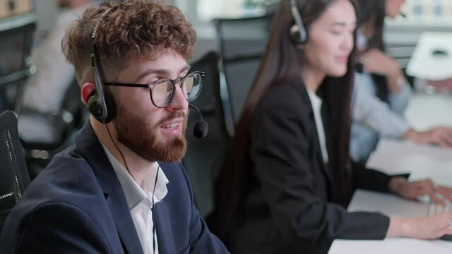 Close Up Portrait of a Technical Customer Support Specialist Talking on a Headset while Working on a Computer in Call center and helpful customer service 24-7. Use desktop pc at computer table and