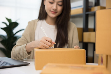 Young asian business woman writing address to sending product to customer. Online business working at home. Startup Small business owner entrepreneur