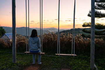 Side View of Mature Woman Sitting on Swing Chair and Looking at Sunrise During Vacation