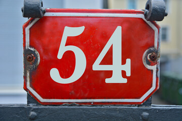 A red number plaque, showing the number fifty-four, 54