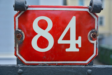 A red number plaque, showing the number eighty-four, 84
