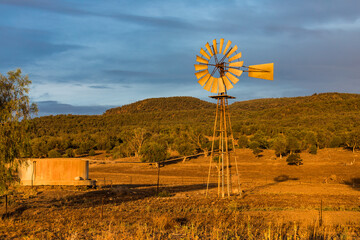 A water pump windmill on a rural farm, late afternoon, in Outback Australia.