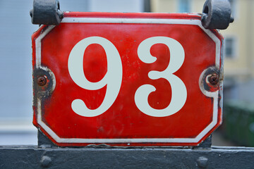 A red number plaque, showing the number ninety-three, 93