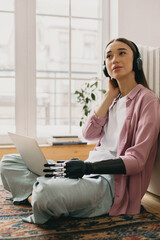 Adorable charismatic photogenic youthful female brunette listening to music in her headphones...