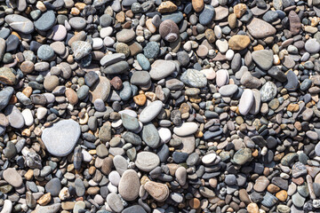Beautiful texture of colorful smooth stones is on the beach by sea