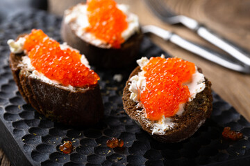 Appetizer with red caviar, cream cheese and rye bread