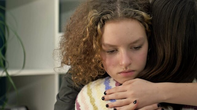 Sad teenage girl hugging her mom or friend.
