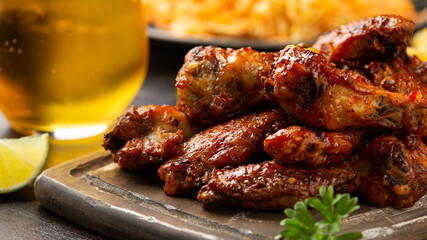 Buffalo chicken wings with beer, french fries on wooden board. fast food