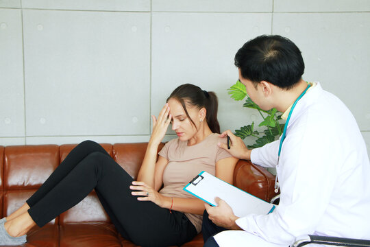 Asian Psychiatrist Man Is Counseling And Encouraging For Caucasian Female Have Mental Health Problems In Clinical Depression Life. Major Depressive Disorder Patients And Healthcare Concept.