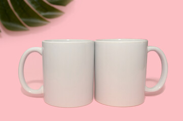 Two white mugs on a pink background. Layout for design. Close-up.