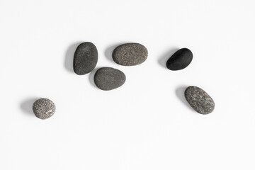 Scattered sea pebble. Smooth gray stones isolated on white background. Flat lay, top view, copy space