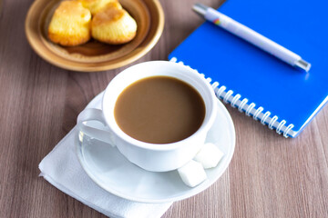 Closeup cup of coffee cookies pen and notepad on the table notebook office bussines work time drink paper note laptop morning bakery food dessert sweet