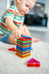 Little girl playing colorful magnet plastic blocks kit at home. The child playing educational games. Early childhood development.