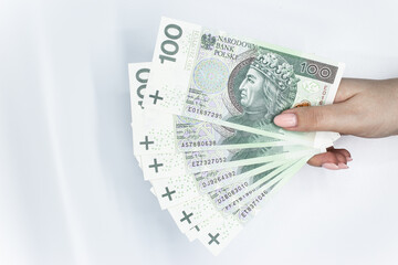 Polish currency held in the hand against a white background