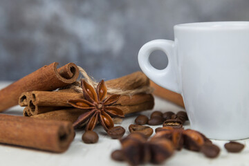 A cup of aromatic black coffee, grains of different varieties on the table. Morning espresso or Americano coffee for breakfast in a beautiful cup. Still life. Cinnamon sticks. 