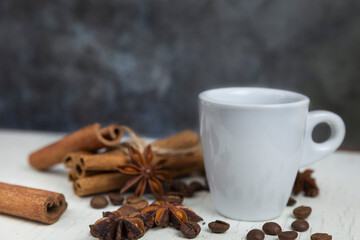 A cup of aromatic black coffee, grains of different varieties on the table. Morning espresso or Americano coffee for breakfast in a beautiful cup. Still life. Cinnamon sticks. 