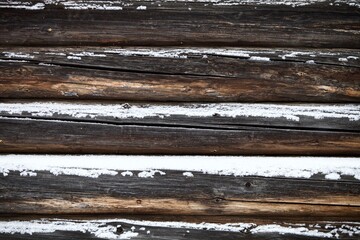 weathered surface of the old wooden log house wall close-up. log walls texture close up. Wooden Log cabin wall in snow close up. The frame of a wooden blockhouse. Vintage log wall surface full frame.