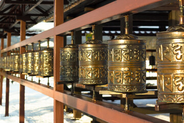 Rows of traditional copper-metal spinning prayer wheels with tibetan holy sacred mantras at snowy...