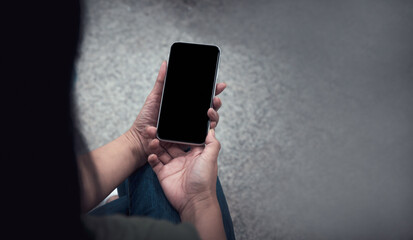 View from the top close-up of a woman's hands clutching a mock-up mobile phone with a blank screen. Smartphone with a blank screen