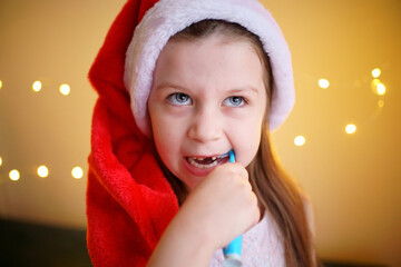 little girl brushing her teeth in Santa hat. High quality photo