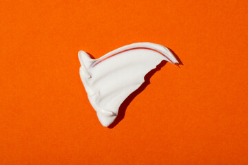 A smear of cream or face mask. The appearance of the texture of the cream on orange background....