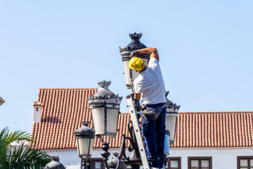 A worker paints vintage Spanish-style street lamps.