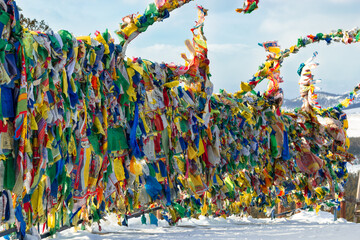 Lots of colorful traditional prayer flags with tibetan mantras hanging out in wind at snowy temple...