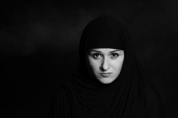 Fototapeta na wymiar beautiful oriental girl in a black open veil on a black background portrait 