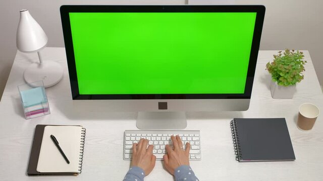 Business woman working in the office at a computer with a green screen on the desktop. Top view. Chroma key.