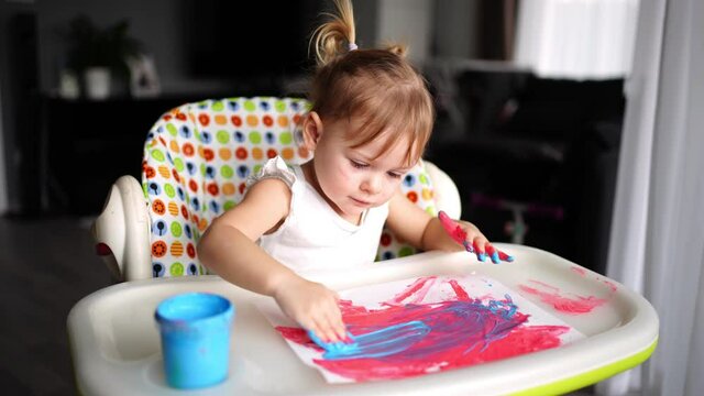 Cute little girl painting with fingers at home. Creative games for kids. Stay at home entertainment