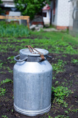 large vertical photo. summer time. aluminum jar in the middle of the garden. environmentally friendly materials on the farm. metal barrel for liquid products.