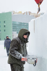 Worker cuts ice panel with gasoline saw