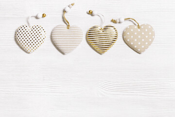 Four handmade hearts from cotton cloth with golden color striped or dots on white wooden background. Valentines Day and love concept, greeting card Valentine postcard. View from above