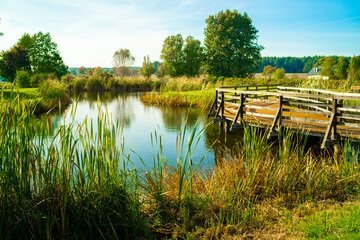 Jezioro w Polsce jesienią obok mały pomost. © Radosaw